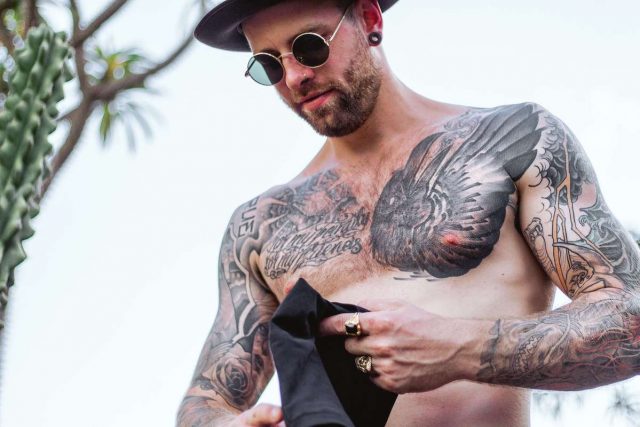 chlap se sexy tetovanim na pláži